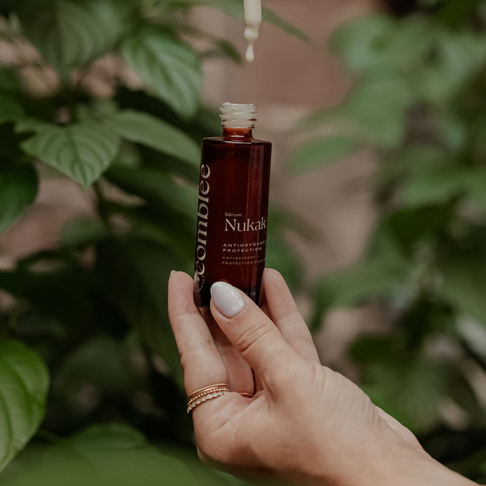 Crème visage Uitoto Comblée tenue entre les mains dans un décor végétal, soin hydratant et réparateur pour peau sensible.