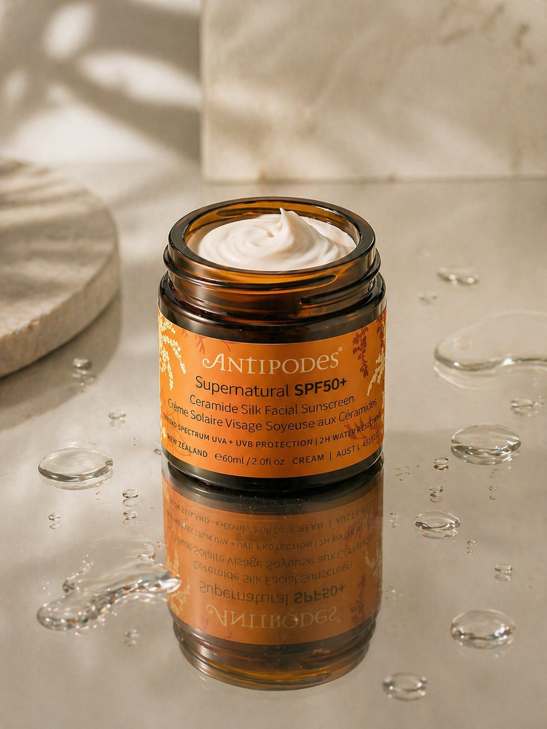 crème solaire visage aux céramides SPF50 posée sur surface avec eau, illustrant protection UV et renforcement de la barrière cutanée