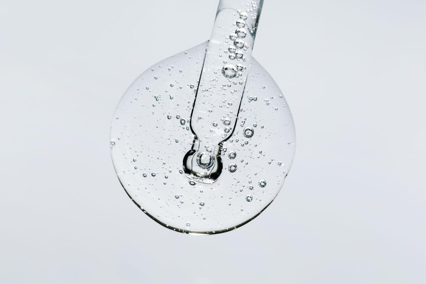Visuel de la page Nos Exclusions Inura illustrant un sérum cosmétique, avec pipette et goutte transparente sur fond clair.