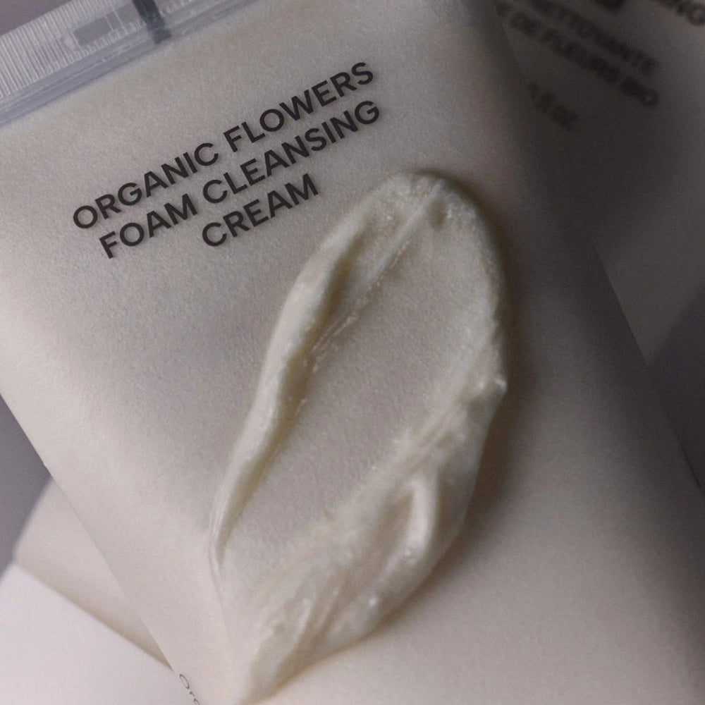 Gros plan de la texture crème du nettoyant visage Whamisa, formule moussante aux fleurs bio fermentées pour une peau fraîche et confortable.