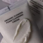 Gros plan de la texture crème du nettoyant visage Whamisa, formule aux fleurs bio fermentées pour une mousse douce.