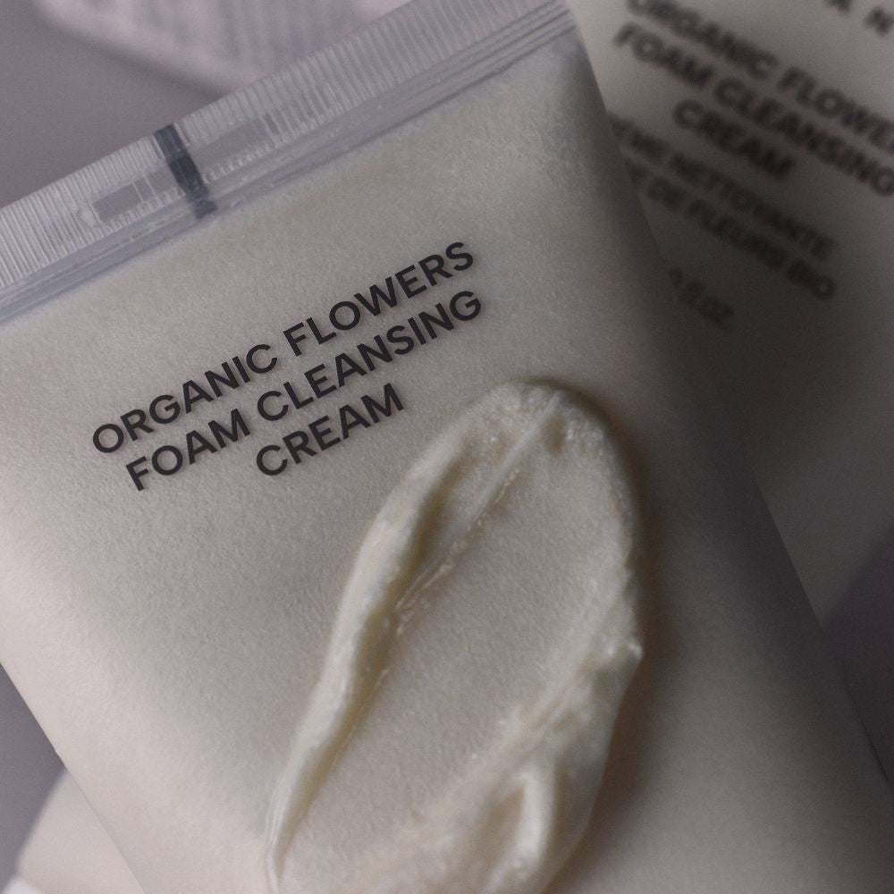 Gros plan de la texture crème du nettoyant visage Whamisa, formule aux fleurs bio fermentées pour une mousse douce.